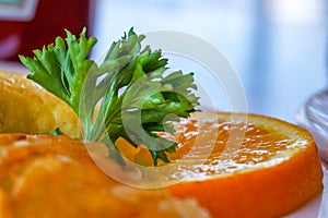 Close up macro-photograph of a parsley and orange slice garnish on a breakfast plate of eggs and hash browns, in a diner,