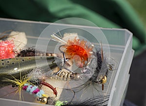 Close up macro of plastic box with colorful fishing flies lure baits, bee, fly and wobler for angling fly-fishing gear