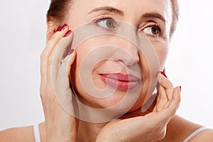 Close-up and macro portrait of beautiful and healthy middle aged woman face on white background. Wrinkles and menopause.