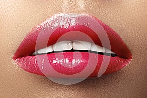 Close-up macro shot of female mouth. Glamour red lips Makeup with sensuality gesture. Magenta gloss lipstick