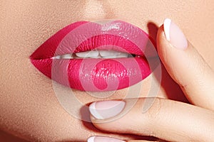 Close-up macro shot of female mouth. Glamour red lips Makeup with sensuality gesture. Magenta gloss lipstick
