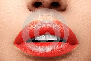 Close-up macro shot of female mouth. Glamour red lips Makeup with sensuality gesture. Orange colour