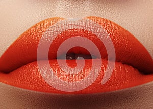 Close-up macro shot of female mouth. Glamour red lips Makeup with sensuality gesture. Orange colour