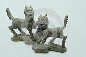 Close-up macro shot of a male and female bronze Chinese Qilin figurines, on white background