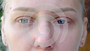 Close-up of macro shot of sad blue eyes. Young beautiful blonde looks into camera. Eyes of girl with long eyelashes