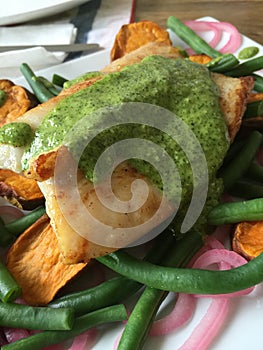 Close up macro shot of seafood dish - fish with pesto sauce and vegetables