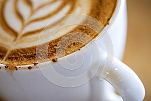 Close up macro shot to hot Cappuccino with white cup on wood tab