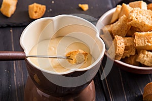 Close up. Traditional french cheese fondue. Crouton dipped into hot fondue with gruyere on a long-stemmed fork.