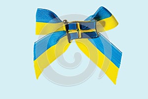 Close up macro view of metal badge in form of swedish flag on blue yellow bow isolate in blue background