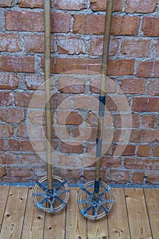 Close up macro view of very old vintage ski poles isolated on brick wall background.