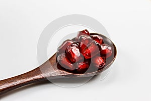 Close up. Macro. A wooden spoon with seeds in it. Wooden spoon with pomegranate seeds isolated on a white background. Fruit