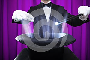 Magician Holding Magic Wand Over Illuminated Hat