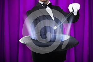 Magician Holding Magic Wand Over Illuminated Hat