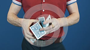 Close up magician in red shirt shuffle playing cards, show Jocker to camera