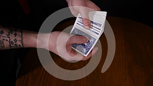 Close-up of a magician`s hands performing card tricks, making fan out cards on black background