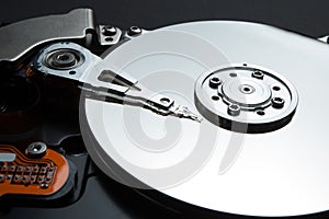 A close-up of a magnetic disk and a reading head on a black background. Restore personal data of users on the hard disk