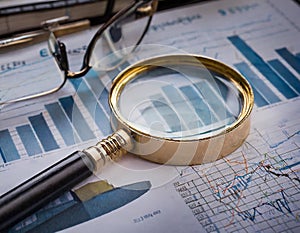 Close-up of a magnifying glass on financial charts and graphs