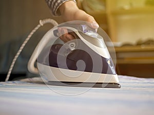 Close up maid hand in the hotel ironing clothes in hotel room white table