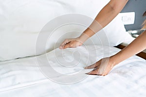 Close up of maid hands set up white bed sheet in hotel room, Free space for text