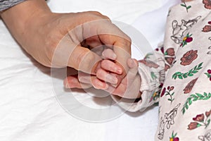 Close up and main focus on newborn baby hand is holding the finger of her mother