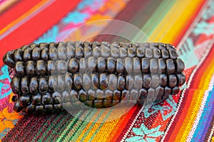 Close up of Maiz Morado, Purple Corn, Zea mays indurata, k\'culli or Black Aztec Corn on a traditional colourful peruvian