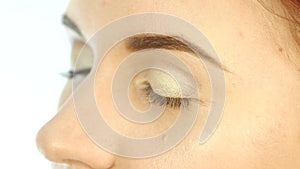 Close-up make-up artist hand, applying eyeshadow to woman`s eye using brush. slow motion