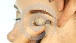 Close-up make-up artist hand, applying eyeshadow to woman`s eye using brush. slow motion