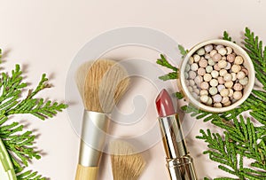 Close up make up brushes and powder, red lipstick on the beige background.