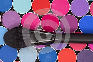 A close-up of  makeup brush and colorful eye shadow palette. Bright colorful background.  View from above