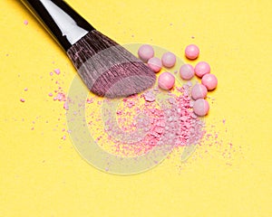 Close-up of makeup brush with crushed and whole shimmer blush ba