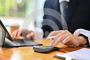 Close up male accountant analyzing sales statistics data on digital tablet and using calculator at working desk