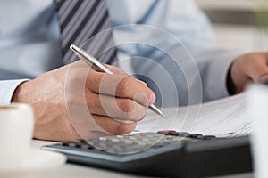 Close up of male accountant making calculations photo