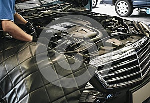 Close up of male auto mechanic working on engine in auto repair