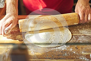 Close up of male baker hands with flour cook roll out the dough with rolling pin