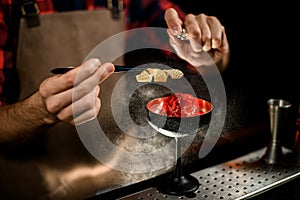 Close-up. Male bartender gently decorates glass with cold drink