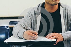 Close up , male with beard , holding pencil exams writing in classroom for education test