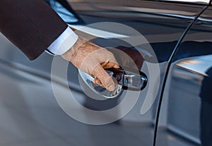 Close up of a male businessman hand opening a car door at the dealership