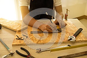 Close-up of male carpenter hands drawing mark on wooden flooring