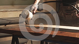 Close-up of a male carpenter`s hands spraying varnish or primer using compressed air on a wooden tabletop. Furniture manufacture