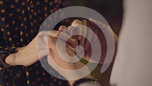 Close-up of male Caucasian hands taking palms of young woman. Unrecognizable couple expressing love outdoors on summer