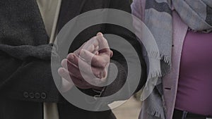 Close-up of male Caucasian hands taking woman`s palm. Adult couple strolling outdoors. Romance, love, marriage, leisure.