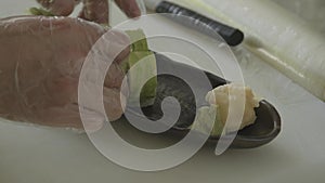 Close up of male chef hands in gloves serving delicious sushi rolls with avocado on a plate