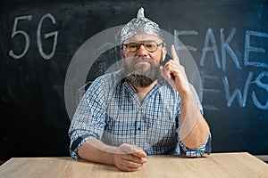 close-up of a male conspiracy theorist in a protective foil cap and glasses debunks myths. Conspiracy theory and the