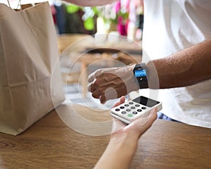 Close Up Of Male Customer In Fashion Store Making Contactless Payment With Smart Watch