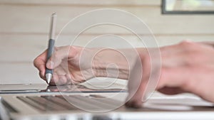 Close-up of a male designer draws on his laptop with help. graphic tablet and pen stylus