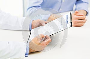 Close up of male doctor and patient with clipboard