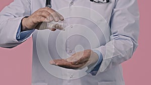 Close up male doctor pouring pills down and holding them in palm, pilules