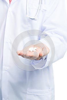 Close-up of male doctor`s hand holding pills for his patient. Young Caucasian men medic wearing professional uniform and