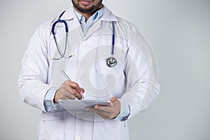 Close up of male doctor using digital tablet over gray background. Medical and healthcare concept