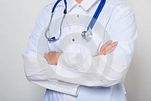 Close-up of a male doctor in a white coat with a stethoscope on his neck, standing with his arms crossed on his chest.